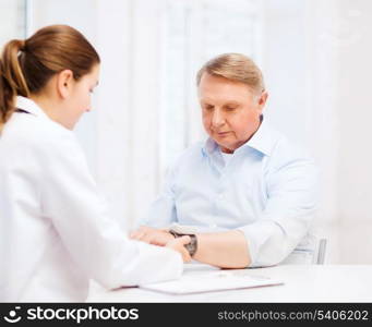 healthcare, elderly and medical concept - female doctor or nurse with male patient measuring blood pressure