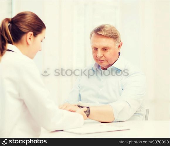 healthcare, elderly and medical concept - female doctor or nurse with male patient measuring blood pressure