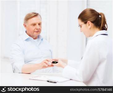 healthcare, elderly and medical concept - female doctor or nurse with patient measuring blood sugar value