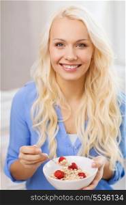 healthcare, food, home and happiness concept - smiling woman with bowl of muesli having breakfast at home