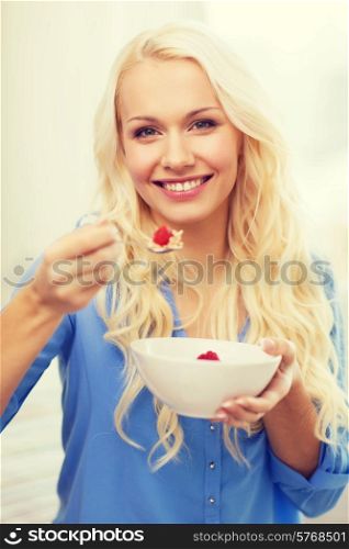 healthcare, food, home and happiness concept - smiling woman with bowl of muesli having breakfast at home