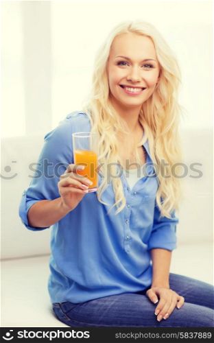 healthcare, food, home and happiness concept - smiling young woman with glass of juice having breakfast at home