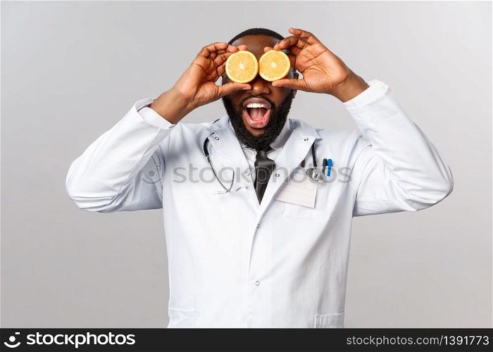 Healthcare, healthy diet and disease concept. Wow so many vitamins. Portrait of amazed happy african-american doctor ask self-distance and eat more vitamins, hold oranges like eyes.. Healthcare, healthy diet and disease concept. Wow so many vitamins. Portrait of amazed happy african-american doctor ask self-distance and eat more vitamins, hold oranges like eyes