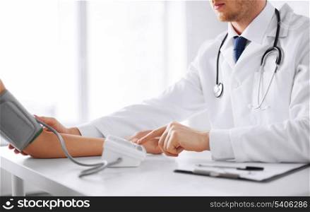 healthcare, hospital and medicine concept - doctor and patient measuring blood pressure