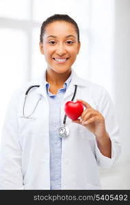 healthcare, medical and cardiology concept - african female doctor with heart