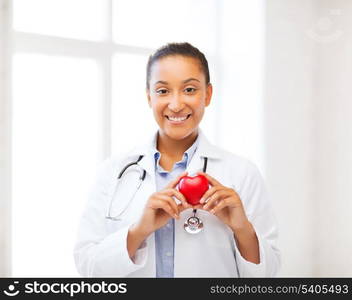 healthcare, medical and cardiology concept - african female doctor with heart