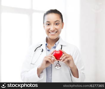 healthcare, medical and cardiology concept - african female doctor with heart