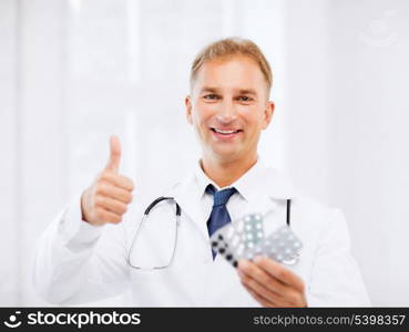 healthcare, medical and pharmacy concept - male doctor with packs of pills