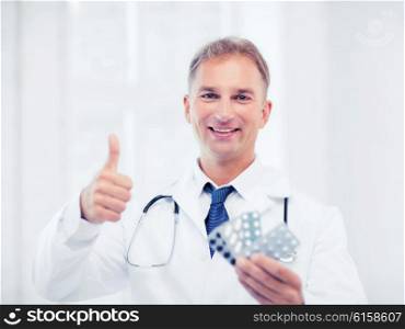 healthcare, medical and pharmacy concept - male doctor with packs of pills
