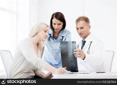 healthcare, medical and radiology concept - doctors with patient looking at x-ray