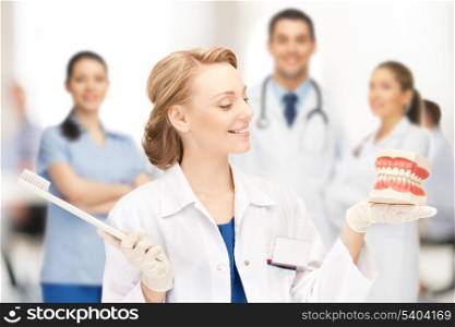 healthcare, medical and stomatology concept - attractive female doctor with toothbrush and big jaws