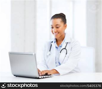 healthcare, medical and technology concept - african female doctor with laptop pc