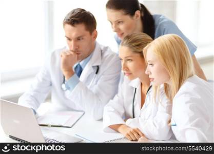 healthcare, medical and technology concept - busy group of doctors looking at laptop computer in hospital