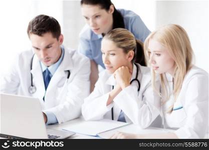 healthcare, medical and technology concept - group of doctors looking at laptop