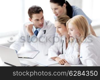 healthcare, medical and technology concept - group of doctors looking at laptop