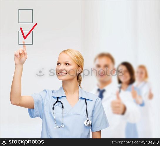 healthcare, medical and technology - young doctor or nurse with marker drawning red checkmark into checkbox with team on the back