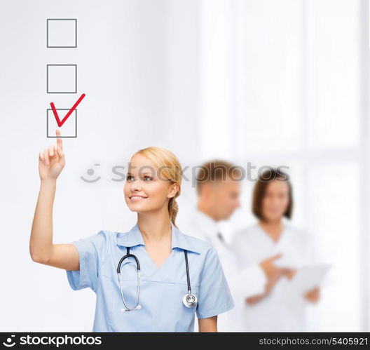 healthcare, medical and technology - young doctor or nurse with marker drawning red checkmark into checkbox with team on the back