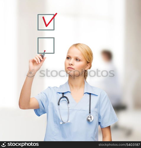 healthcare, medical and technology - young doctor or nurse with marker drawning red checkmark into checkbox