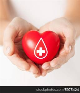 healthcare, medicine and blood donation concept - female hands holding red heart with donor sign