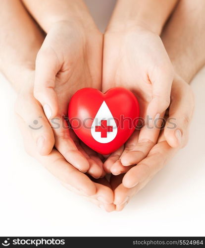 healthcare, medicine and blood donation concept - male and female hands holding red heart with donor sign