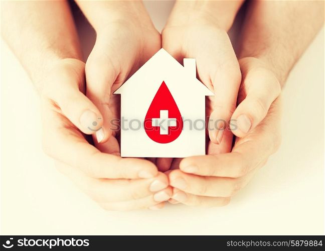 healthcare, medicine and blood donation concept - male and female hands holding hands holding white paper house with red donor sign