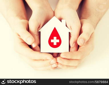 healthcare, medicine and blood donation concept - male and female hands holding hands holding white paper house with red donor sign