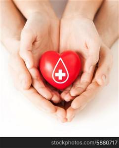 healthcare, medicine and blood donation concept - male and female hands holding red heart with donor sign