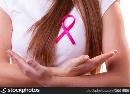 Healthcare, medicine and breast cancer awareness concept - Closeup of pink badge ribbon on woman chest to support breast cancer cause. Pink ribbon on woman chest to support breast cancer cause