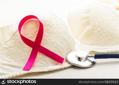 Healthcare, medicine and breast cancer awareness concept. Closeup pink ribbon and stethoscope on female bra.