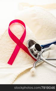 Healthcare, medicine and breast cancer awareness concept. Closeup pink ribbon and stethoscope on female bra.