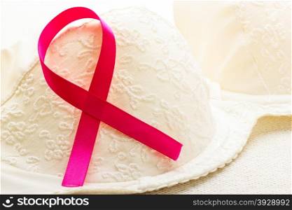 Healthcare, medicine and breast cancer awareness concept. Closeup pink ribbon on female bra.