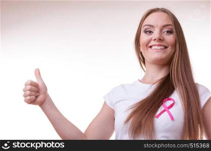 Healthcare, medicine and breast cancer awareness concept. Content young woman with pink cancer ribbon on chest making thumb up hand gesture. woman pink cancer ribbon on chest making thumb up