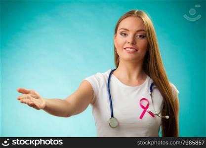 Healthcare, medicine and breast cancer awareness concept. Doctor with pink ribbon formed Aids symbol, inviting making welcome hand gestureon blue