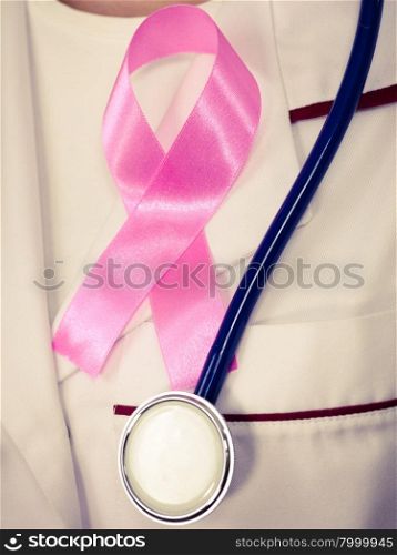Healthcare, medicine and breast cancer awareness concept. Doctor with stethoscope and pink ribbon aids symbol on chest closeup