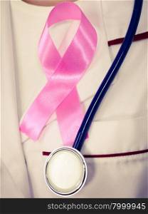 Healthcare, medicine and breast cancer awareness concept. Doctor with stethoscope and pink ribbon aids symbol on chest closeup