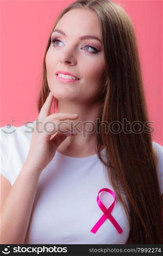 Healthcare, medicine and breast cancer awareness concept - thinking woman in t-shirt with pink cancer ribbon on red
