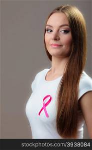 Healthcare, medicine and breast cancer awareness concept - woman in t-shirt with pink cancer ribbon on gray