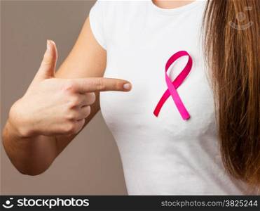 Healthcare, medicine and breast cancer awareness concept. Woman in t-shirt with pink cancer ribbon pointing