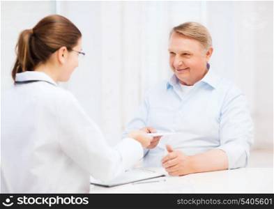 healthcare, medicine and elderly concept - female doctor or nurse with old man giving prescription