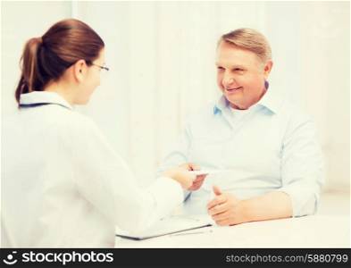 healthcare, medicine and elderly concept - female doctor or nurse with old man giving prescription