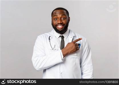 Healthcare, medicine and epidemic concept. Cheerful, friendly-looking african-american male physician explain patients prevention of getting covid19 symptoms, poiting finger right, recommend product.. Healthcare, medicine and epidemic concept. Cheerful, friendly-looking african-american male physician explain patients prevention of getting covid19 symptoms, poiting finger right, recommend product