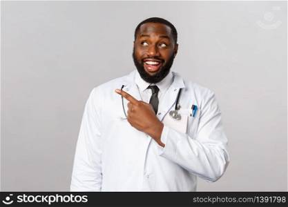 Healthcare, medicine and epidemic concept. Curious and excited, happy doctor, african-american physician seeing cool new medication, pointing finger and looking upper left corner.. Healthcare, medicine and epidemic concept. Curious and excited, happy doctor, african-american physician seeing cool new medication, pointing finger and looking upper left corner