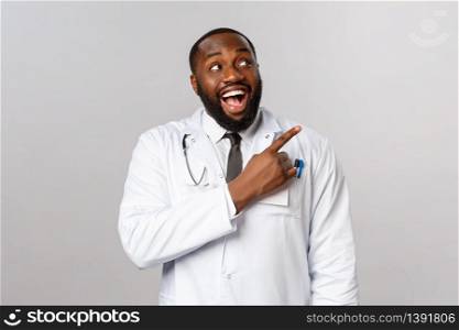 Healthcare, medicine and epidemic concept. Excited, happy and amused smiling african-american doctor pleased with new product in pharmacy store, pointing finger right, recommend this pills.. Healthcare, medicine and epidemic concept. Excited, happy and amused smiling african-american doctor pleased with new product in pharmacy store, pointing finger right, recommend this pills