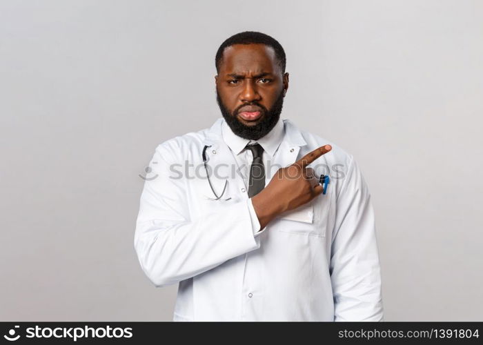 Healthcare, medicine and epidemic concept. Serious-looking angry and frustrated african-american doctor scolding patient not taking care health, pointing finger right and stare with judgement.. Healthcare, medicine and epidemic concept. Serious-looking angry and frustrated african-american doctor scolding patient not taking care health, pointing finger right and stare with judgement