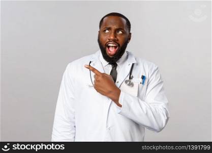 Healthcare, medicine and epidemic concept. Shocked and startled, upset african-american doctor seeing something cringy and shocking, pointing looking upper left corner frustrated.. Healthcare, medicine and epidemic concept. Shocked and startled, upset african-american doctor seeing something cringy and shocking, pointing looking upper left corner frustrated