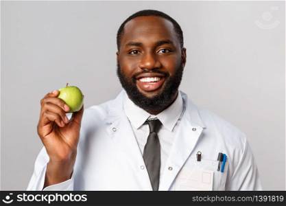 Healthcare, medicine and hospital treatment concept. Close-up portrait of friendly physician, happy smiling doctor explain the importance of staying healthy, eat vitamins, show green apple.. Healthcare, medicine and hospital treatment concept. Close-up portrait of friendly physician, happy smiling doctor explain the importance of staying healthy, eat vitamins, show green apple