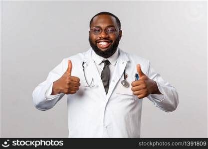 Healthcare, medicine and hospital treatment concept. Happy satisfied african-american bearded doctor in glasses and white coat, show thumb-up relieved, tell patient their test result is fine.. Healthcare, medicine and hospital treatment concept. Happy satisfied african-american bearded doctor in glasses and white coat, show thumb-up relieved, tell patient their test result is fine