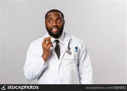 Healthcare, medicine and hospital treatment concept. Thoughtful handsome young doctor, african-american therapist thinking what order for food at lunch, bite glasses rim and look up daydreaming.. Healthcare, medicine and hospital treatment concept. Thoughtful handsome young doctor, african-american therapist thinking what order for food at lunch, bite glasses rim and look up daydreaming