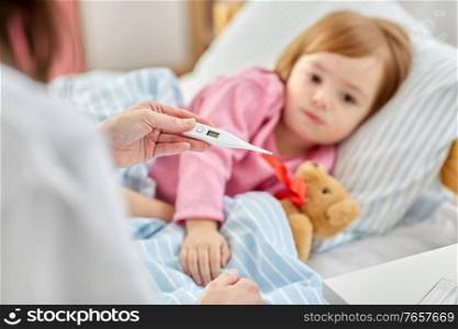 healthcare, medicine and people concept - close up of doctor with thermometer measuring temperature of little sick girl lying in bed at home. doctor measuring sick girl&rsquo;s temperature