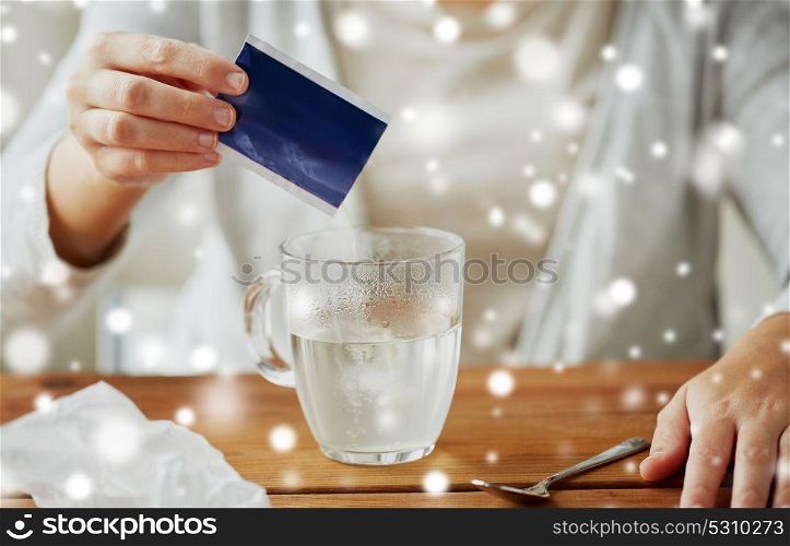 healthcare, medicine and people concept - close up of ill woman pouring medication powder into class mug with spoon over snow. close up of ill woman pouring medication into cup